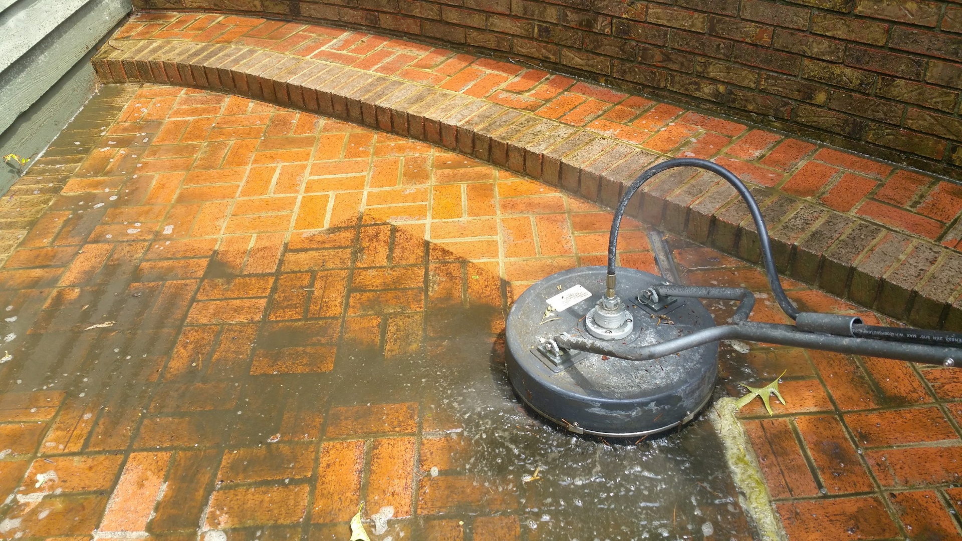 Pressure washing surface cleaner on brick patio