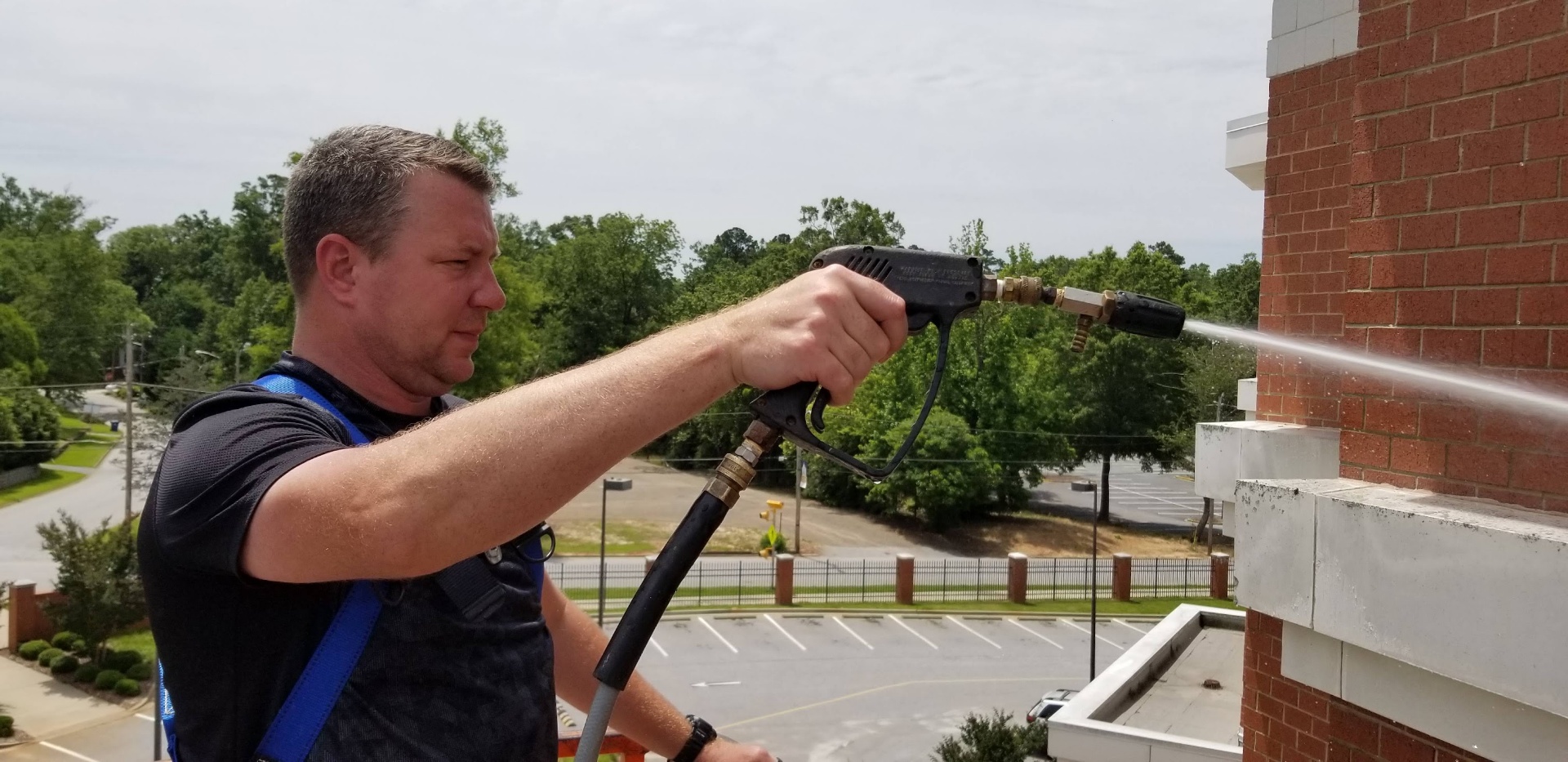 Technician pressure washing commercial brick exterior